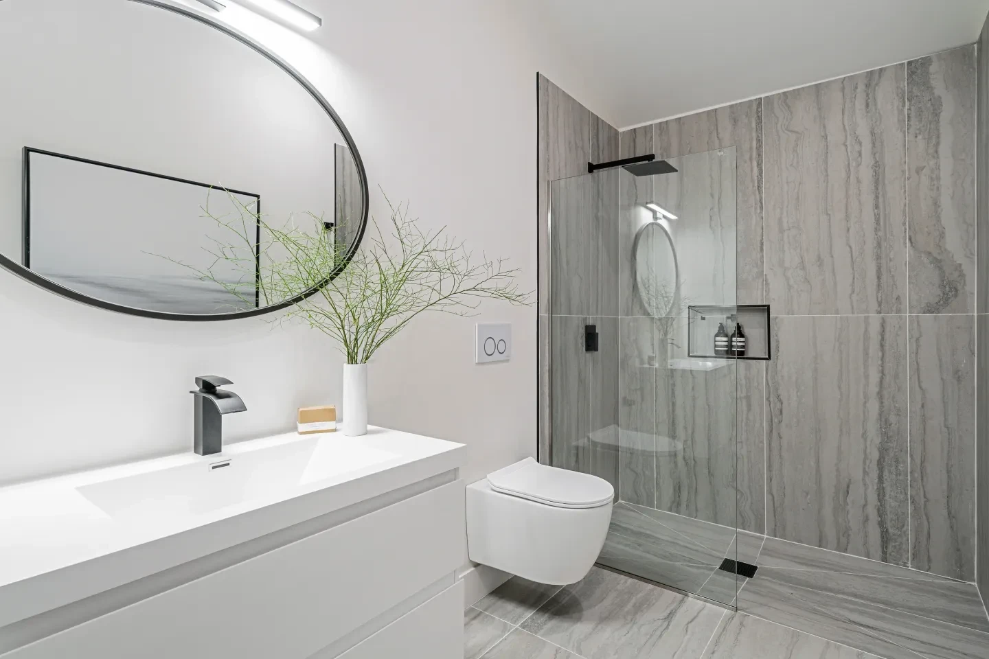 Modern bathroom with grey stone tile and round mirror