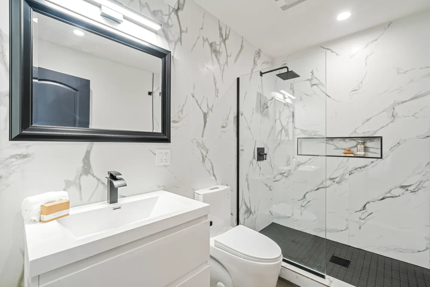 Modern bathroom with white marble walls and black fixtures