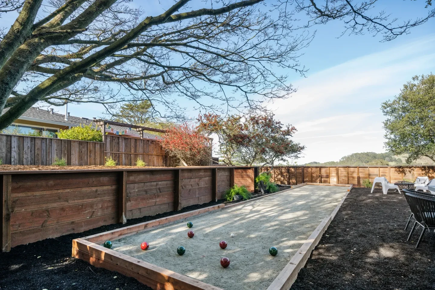Backyard bocce ball court with wooden fencing and landscaping