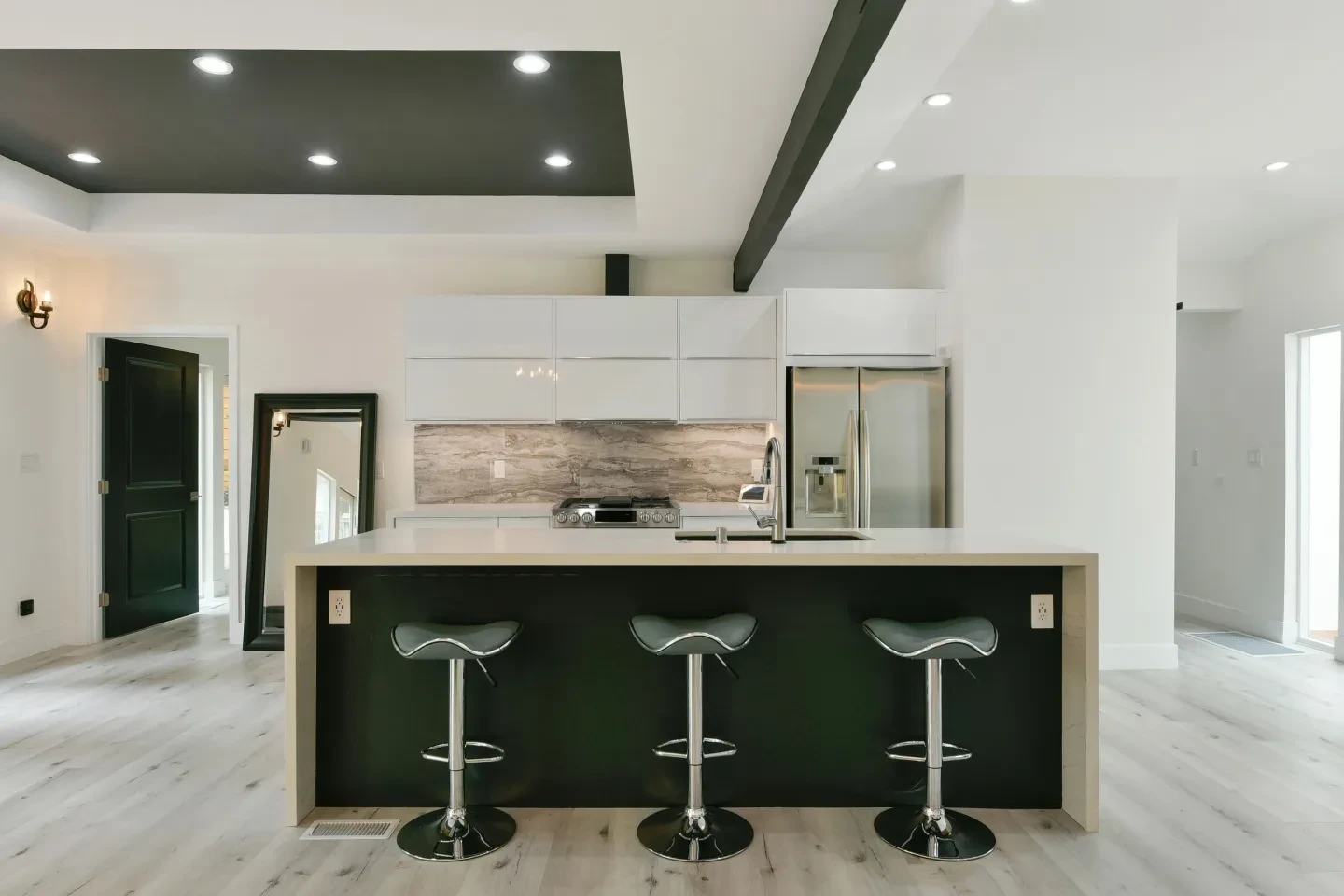 Modern kitchen with white cabinetry and dark green island