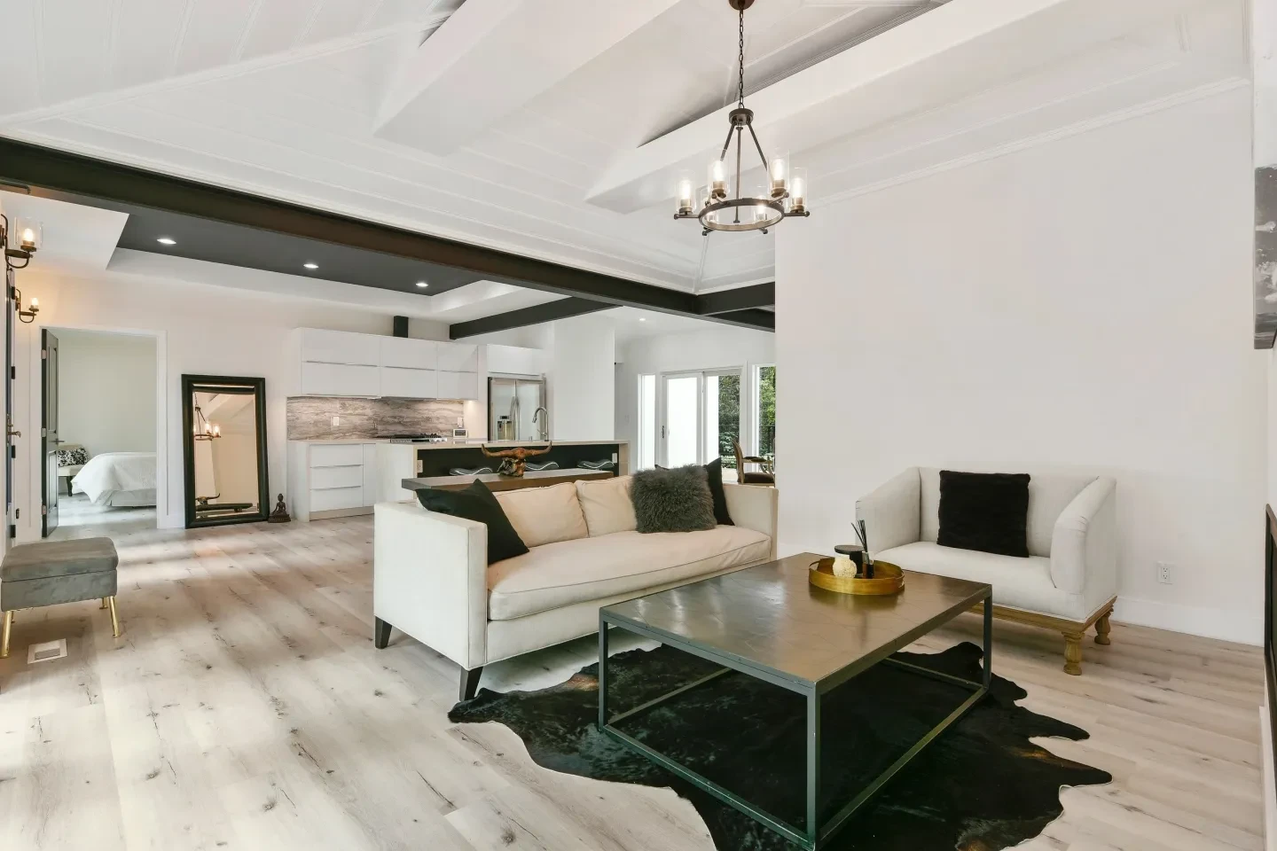 Modern open concept living room with beamed ceilings and chandelier