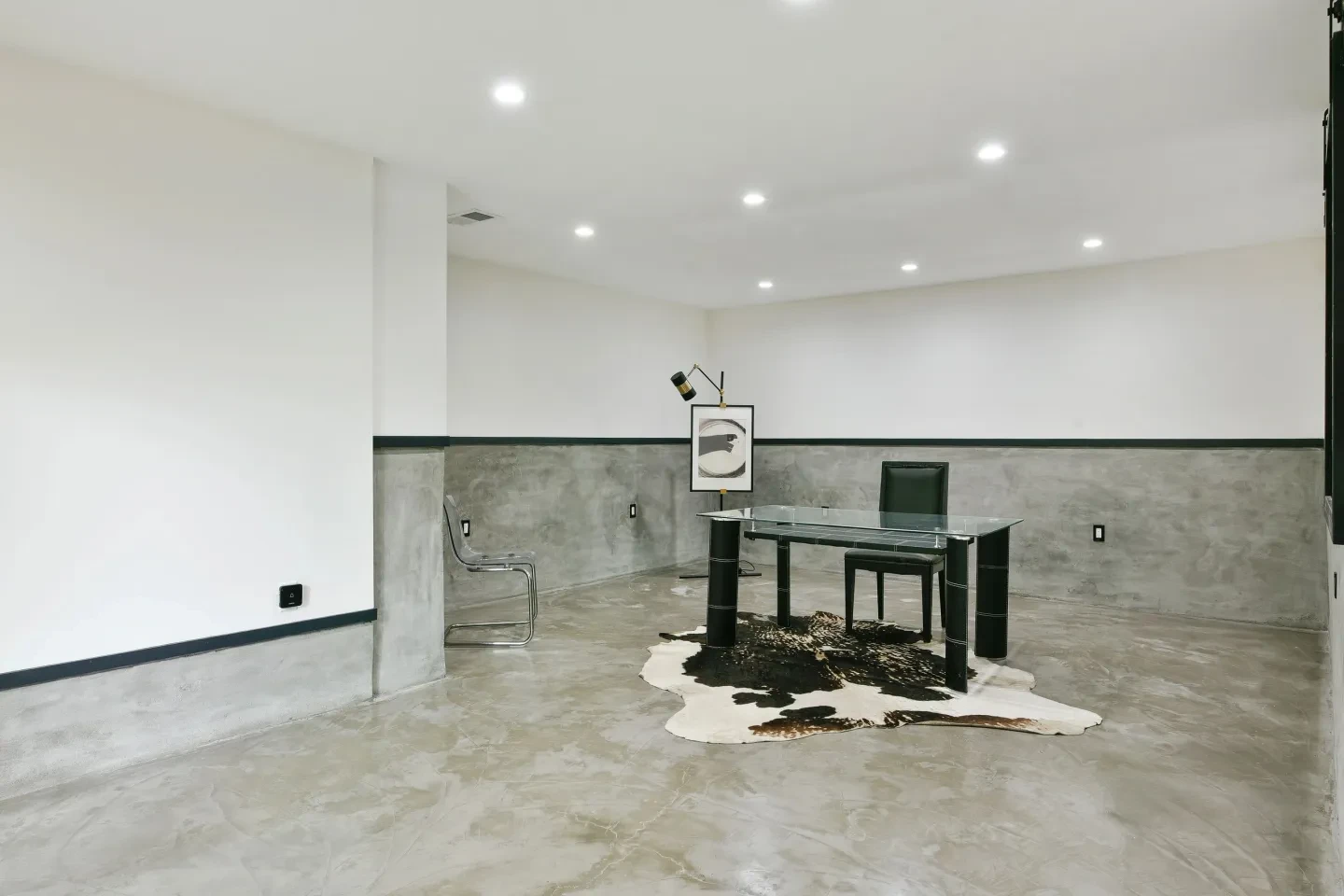 Minimalist concrete office space with glass desk and cowhide rug