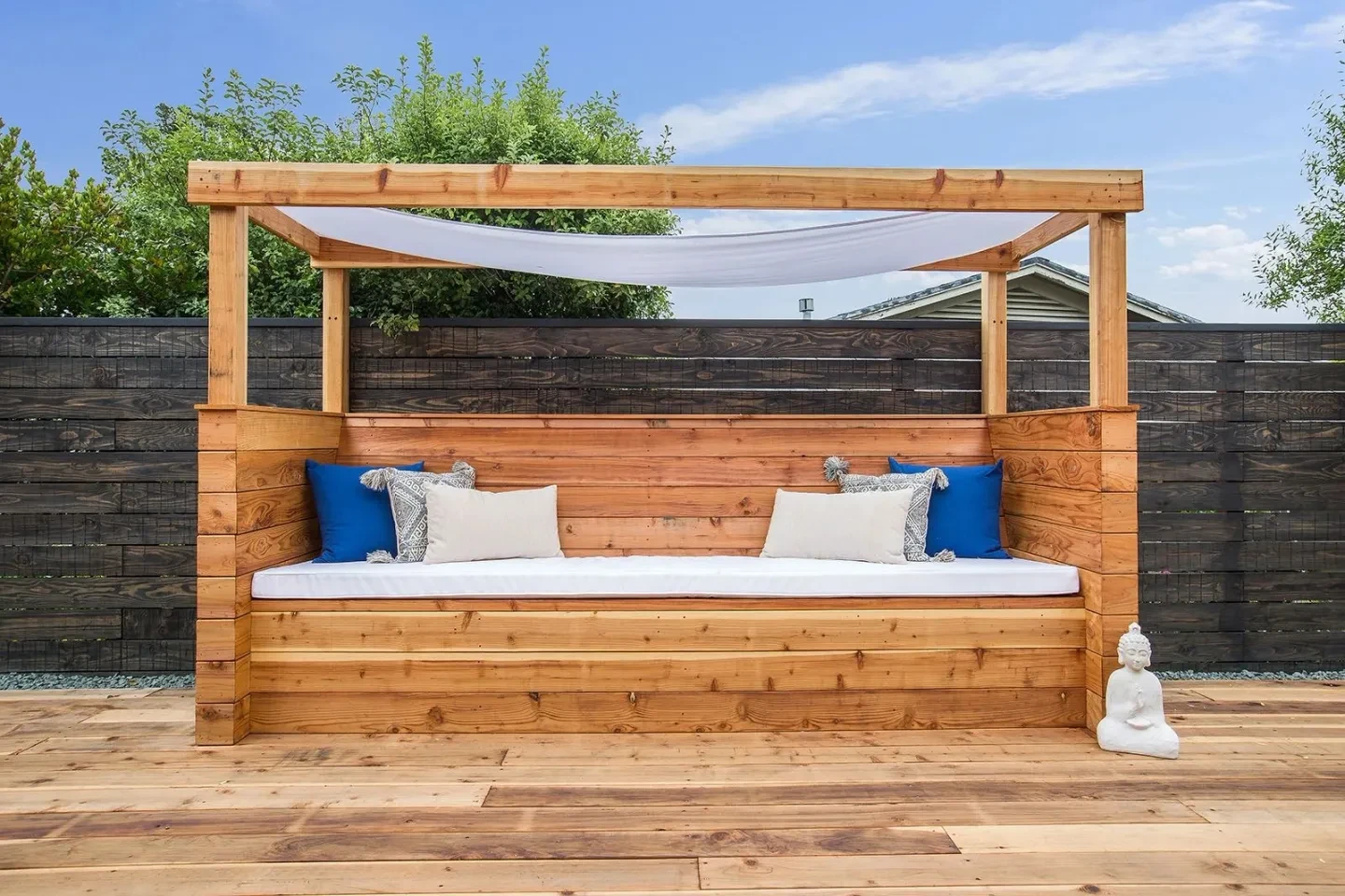 Outdoor wooden daybed with pergola canopy and blue pillows