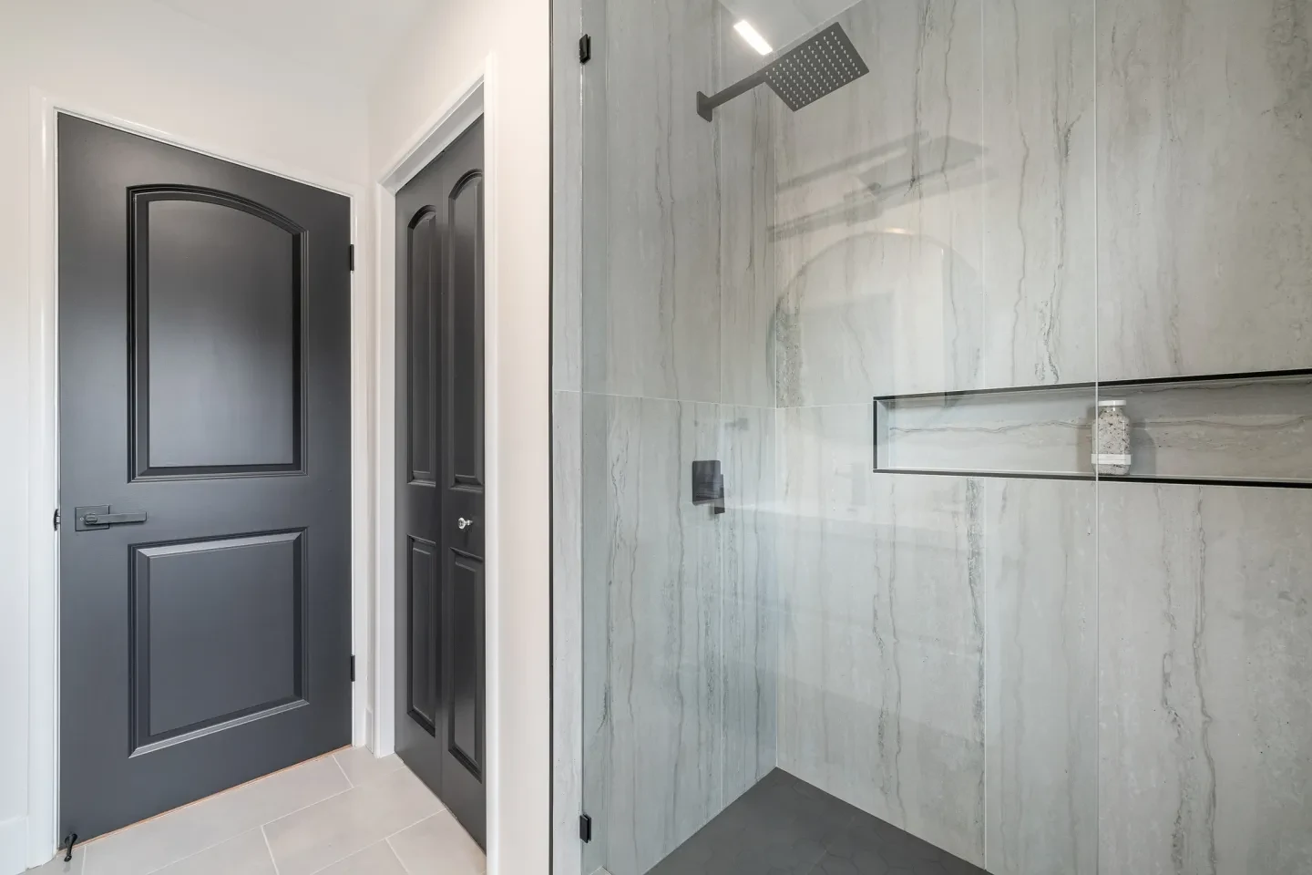 Modern bathroom with dark charcoal door and marble shower enclosure